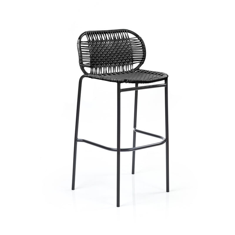 The Ames Cielo Barstool by Ames features a black, woven rattan-style backrest and seat on slim metal legs with a footrest, offering a sleek, modern look reminiscent of Sebastian Herkner’s style against a plain white background.