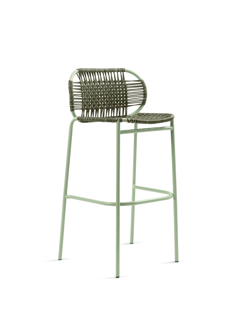 The Ames Cielo Barstool by Ames features a sage green metal frame, woven backrest, and matching seat. Its open, modern design and footrest bar make it a stylish, comfortable seating option inspired by the original Cielo Bar Stool.