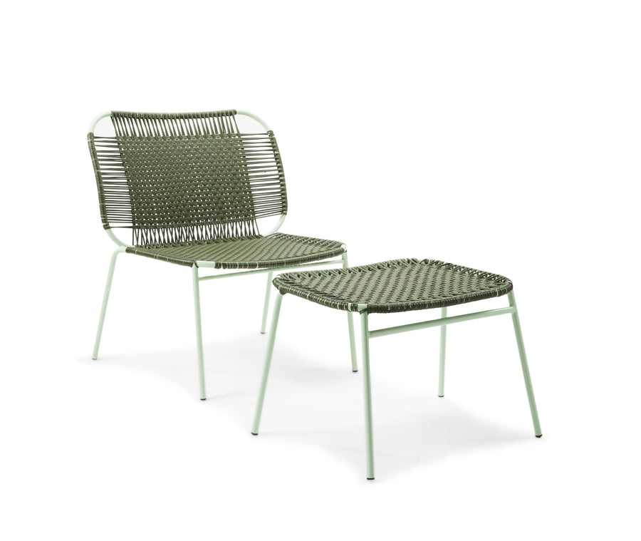 A green woven chair with thin metal legs is paired with the Ames Cielo Ottoman by Ames, both showcasing a minimalist design inspired by traditional weaving, set against a white background.