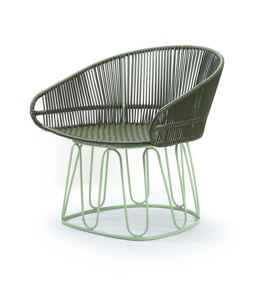 The Ames Circo Leather Lounge Chair by Ames features a modern, open, rounded design with an olive green woven rope seat and backrest on a light green metal wire base. This handcrafted Colombian piece is shown against a white background.