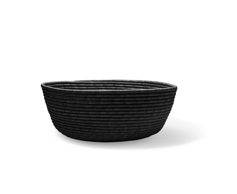 The Ames La Che Basket by Ames is a handmade, round black basket crafted from Fique fibers with a ribbed, textured surface, shown on a white background with a soft shadow.