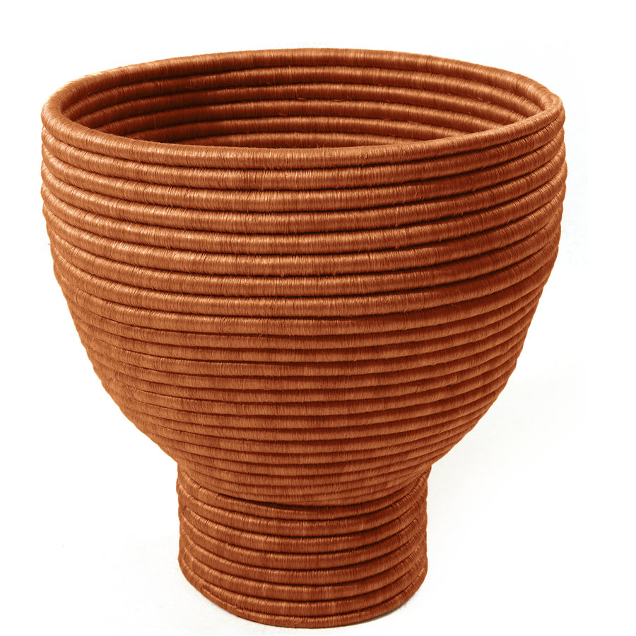 The Ames La Che Pot by Ames is a large, round bowl with a narrow base, crafted from coiled fique fiber for a textured, layered look inspired by Colombian culture.