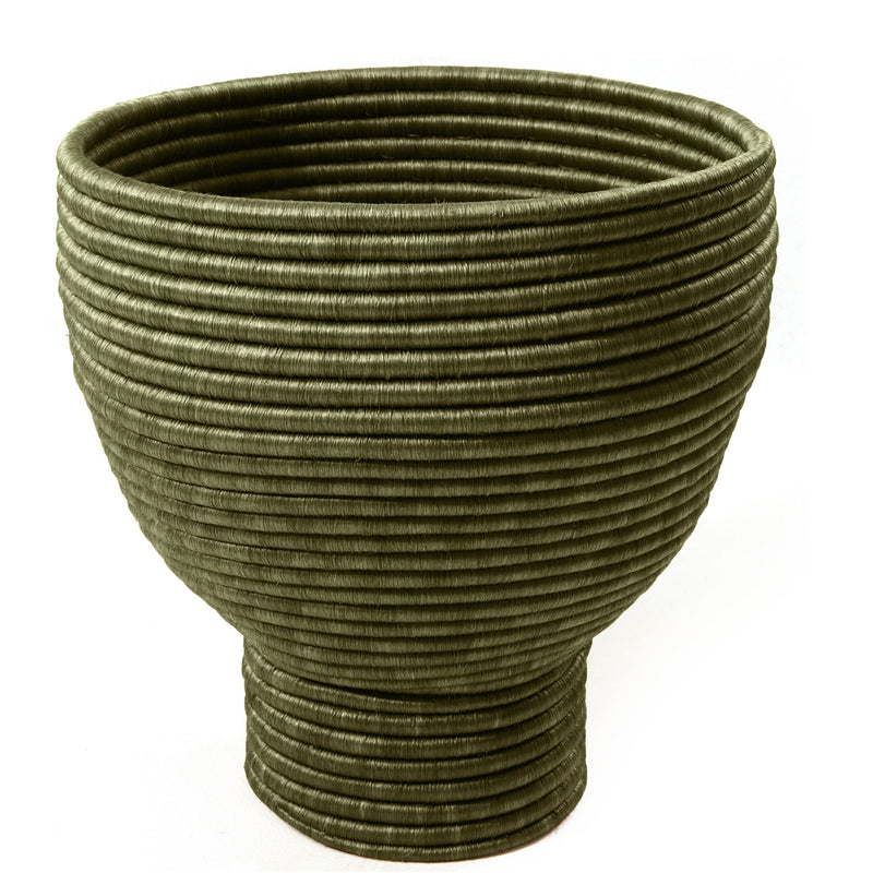 The Ames La Che Pot by Ames is a large, olive green bowl with a unique ribbed texture, handcrafted from natural fique fiber in horizontal rings—a modern nod to traditional Colombian culture.