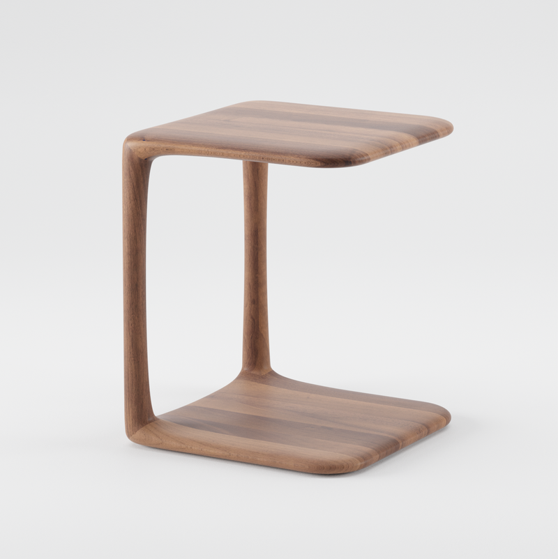 The BLEND Side Table by Artisan is a modern, minimalist piece with a C-shaped design made of solid wood and an eco-friendly, smooth, natural finish. Featuring rounded corners, it rests steadily against a white background.