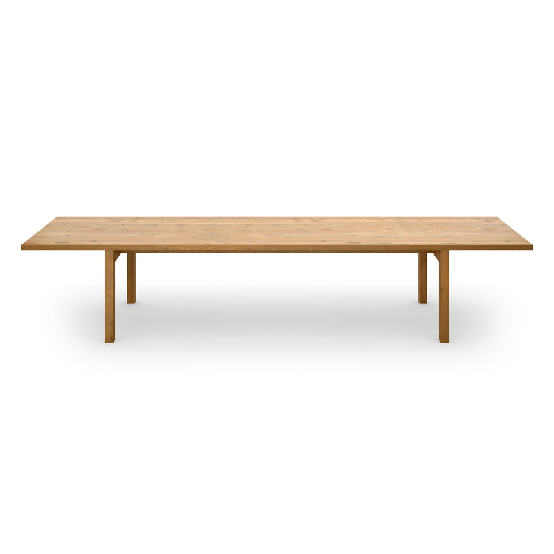 The DC09 Galerie by E15 is a long, rectangular solid oak table with a minimalist design, featuring four simple legs and a smooth surface. Positioned against a plain white background, it embodies the simplicity and elegance reminiscent of the Neue Nationalgalerie table.