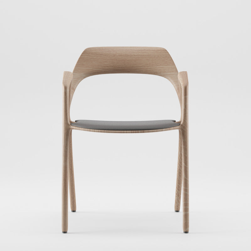 The Ging Chair from Artisan is a modern wooden chair with a minimalist design, featuring a curved backrest and an eco-friendly dark cushioned seat. Photographed against a plain white background, it embodies the ArtisanDesigner Way Object ethos.