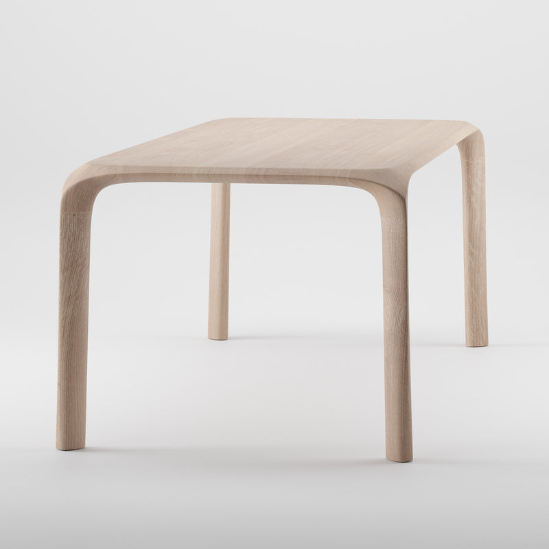 The Artisan Ging Table is a minimalist design crafted from solid wood, featuring smoothly curved legs and a square top. Its light wood finish highlights the organic beauty of wood, offering a sleek modern look with gentle curves on corners and legs.
