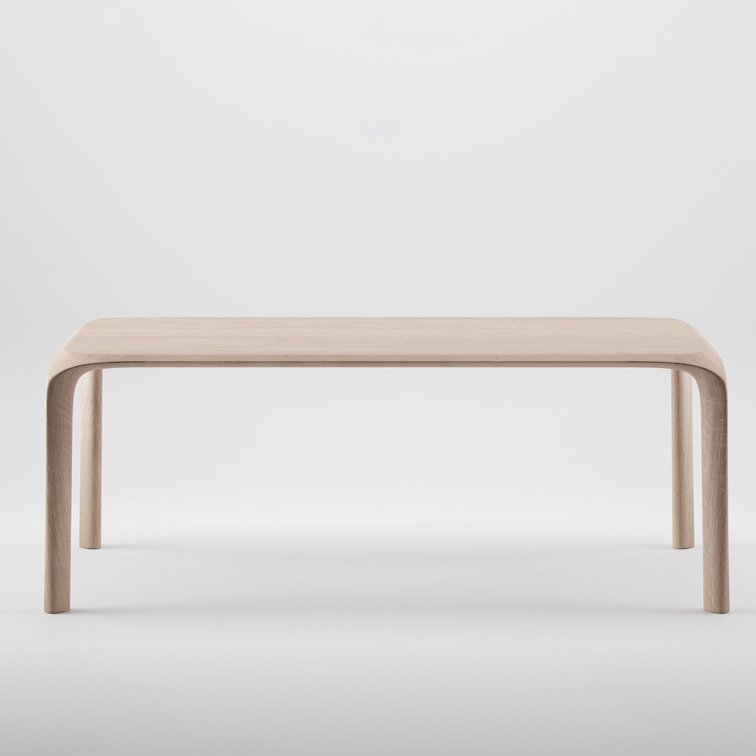The Artisan Ging Table is a minimalist, solid wood table featuring gently curved legs and a smooth, light finish. Set against a plain white background, it highlights the organic beauty and simple elegance of its design.