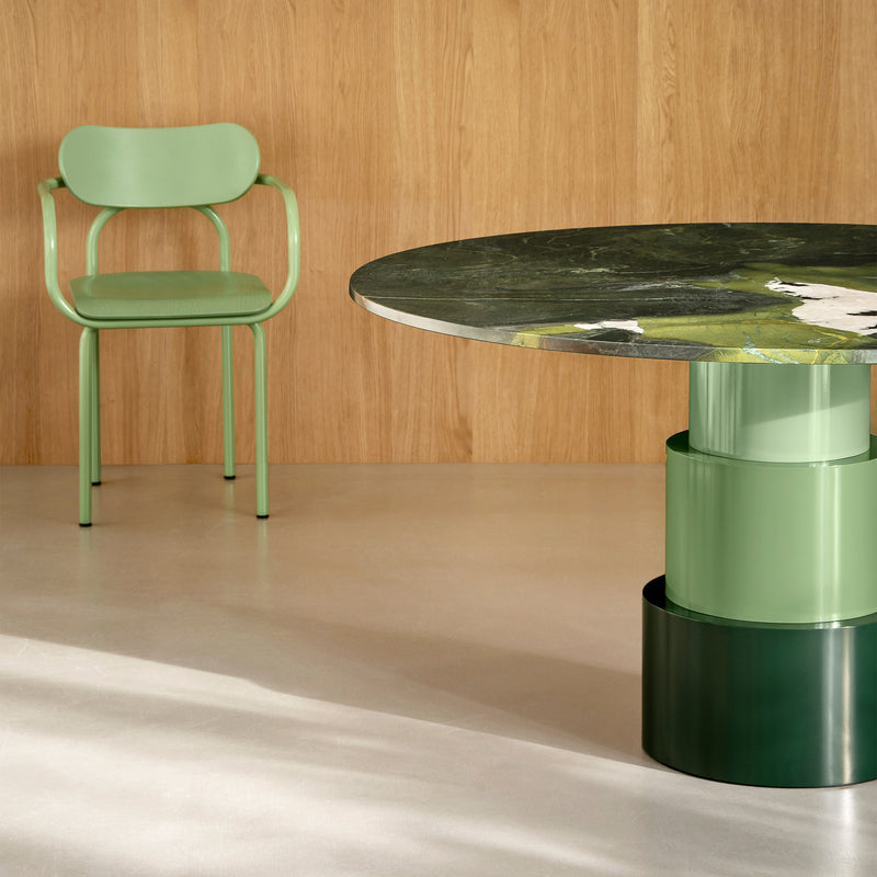 U Turn Table Avocatus with polished green Avocatus top and sage green base next to matching chair on light floor.