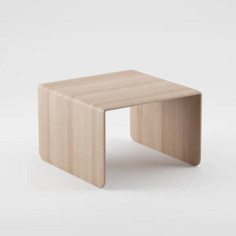 The INVITO Coffee Table by Artisan is a minimalist piece crafted from solid wood, featuring a natural finish and a sleek, U-shaped design. Its smooth, curved corners sit against a white background, showcasing its simple modern aesthetic and organic beauty.