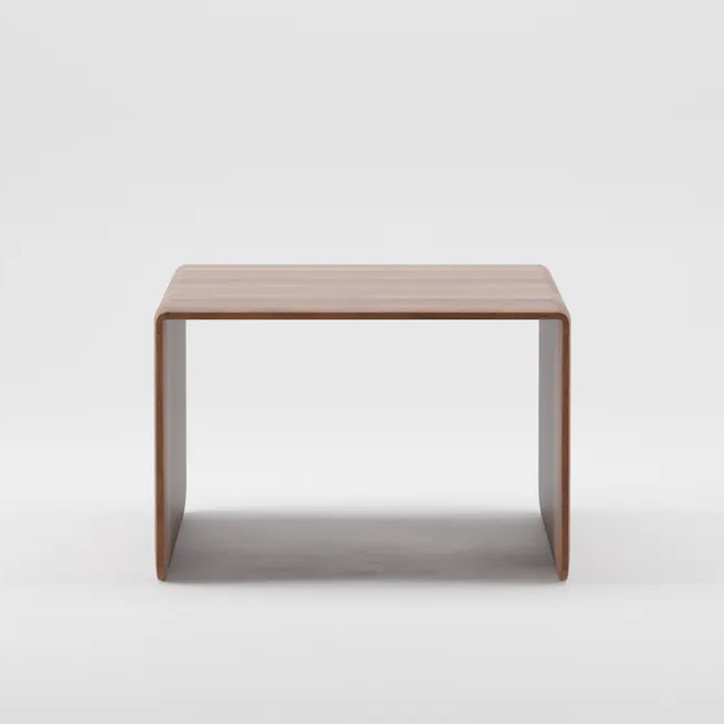 The INVITO Coffee Table by Artisan is a minimalist rectangular piece made from solid wood. It features smooth, rounded edges with legs continuous to the top surface, showcasing organic beauty against a plain white background.