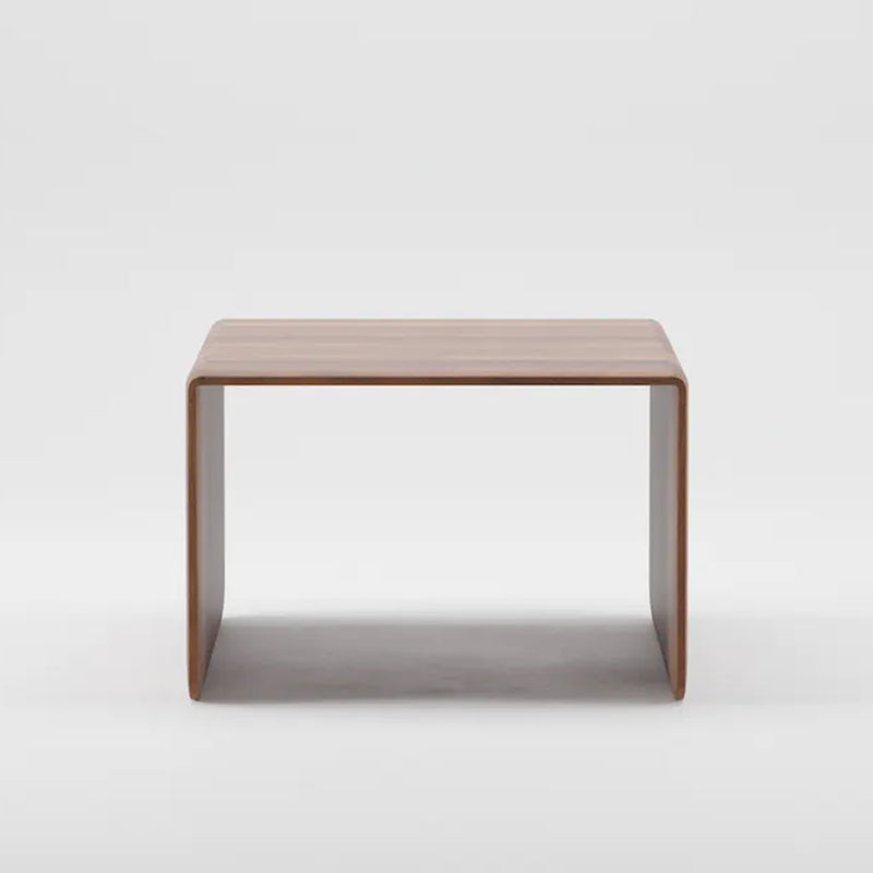The INVITO Coffee Table by Artisan is a minimalist rectangular piece made from solid wood. It features smooth, rounded edges with legs continuous to the top surface, showcasing organic beauty against a plain white background.