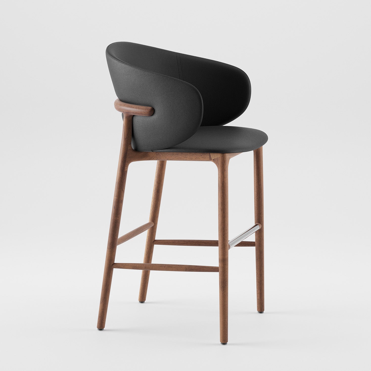 The Artisan Mela Bar Chair combines a sleek wooden frame with a black upholstered backrest. Its mid-century design has clean lines and a metal footrest, standing elegantly on a plain white background.