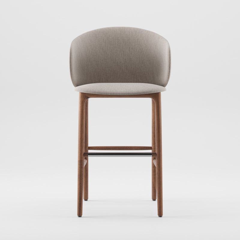 The Mela Bar Chair by Artisan is a modern, mid-century-inspired stool with a light grey fabric seat and upholstered backrest. It boasts a wooden frame with four legs and a footrest, combining minimalist and contemporary design elements.