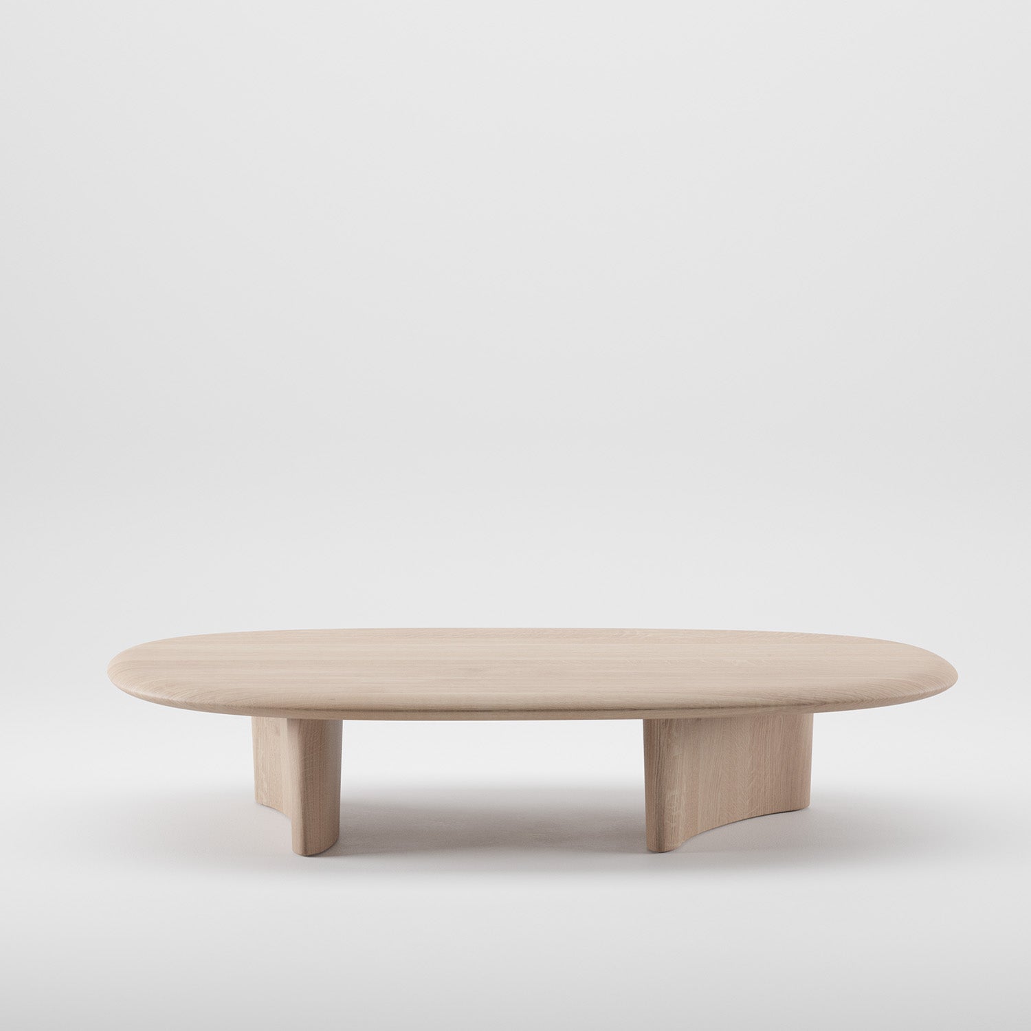 The MONUMENT Oval Coffee Table by Artisan features a minimalist design with an oval shape crafted from solid, light wood. Its flat top and elegantly curved legs are finished with natural oils, enhancing its eco-friendly appeal against a simple white backdrop.