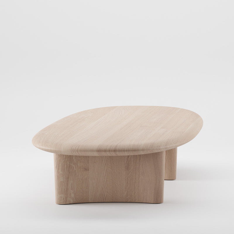 The MONUMENT Oval Coffeetable by Artisan is a minimalist, environmentally-friendly wooden coffee table made from solid wood. It features an oval top and curved legs enriched with natural oils, set against a plain white background.