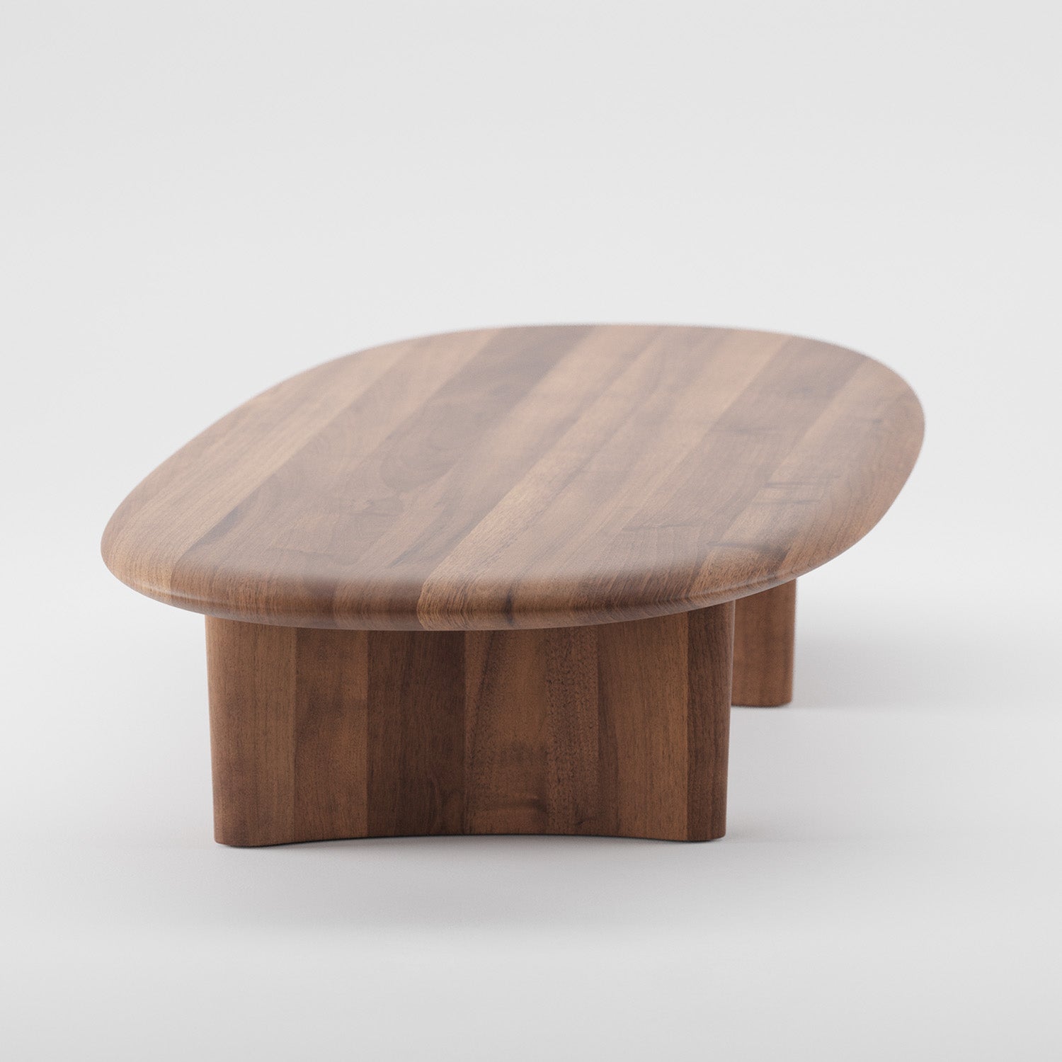 The Artisan MONUMENT Oval Coffeetable is a modern piece with a polished finish using natural oils. It has a thick, flat top and wide, sturdy base, crafted from solid dark wood and set against a plain white background.