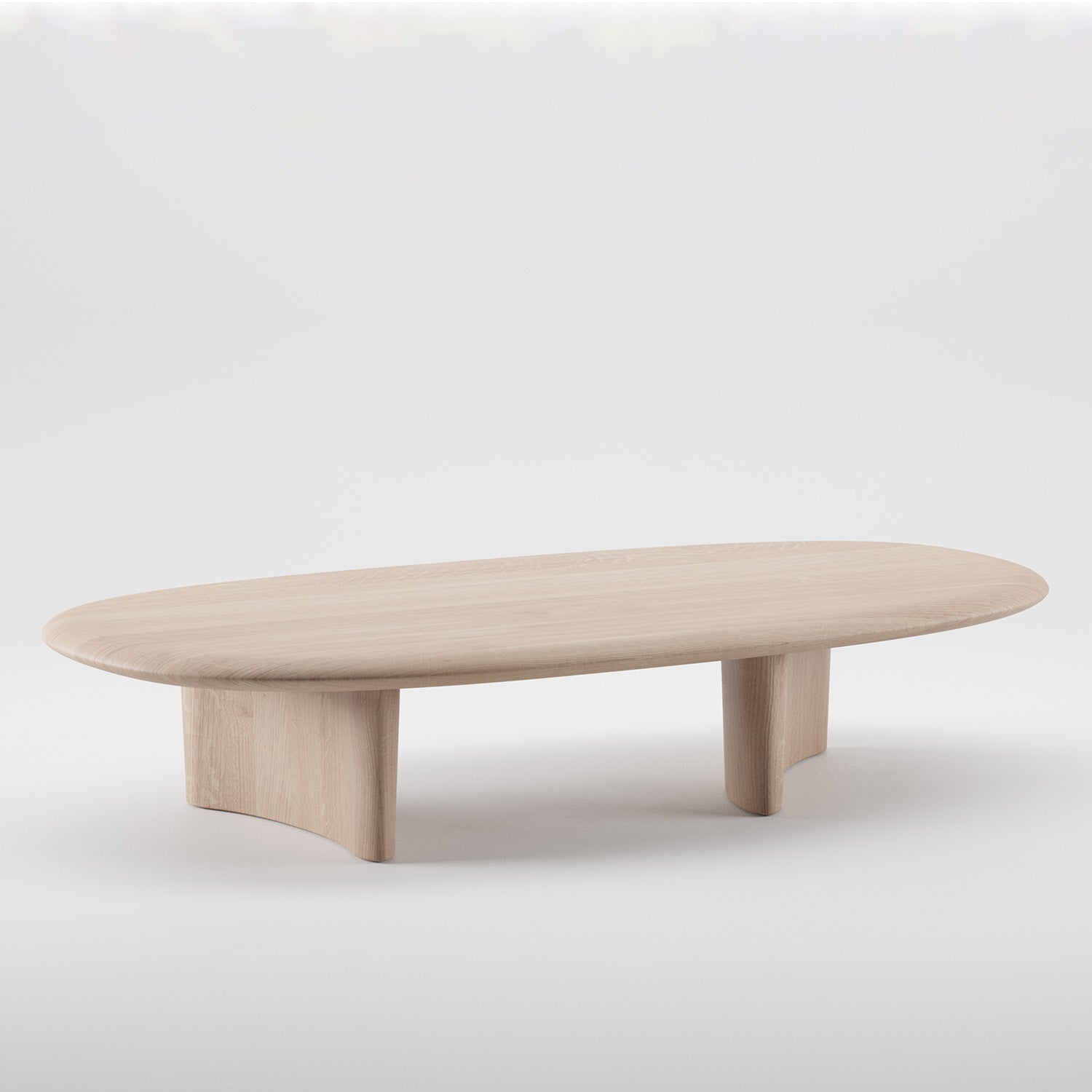 The MONUMENT Oval Coffee Table by Artisan is a minimalist design crafted from solid wood with a light finish. It features two wide, curved legs for support and is made using environmentally-friendly materials, all set against a plain white background.