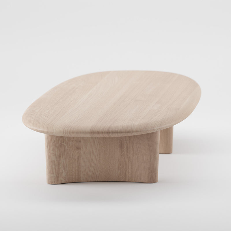The MONUMENT Oval Coffeetable by Artisan is a minimalist piece crafted from eco-friendly materials, showcasing a smooth oval top and thick rounded legs. Set against a plain white background, it highlights the natural wood grain and simple design.