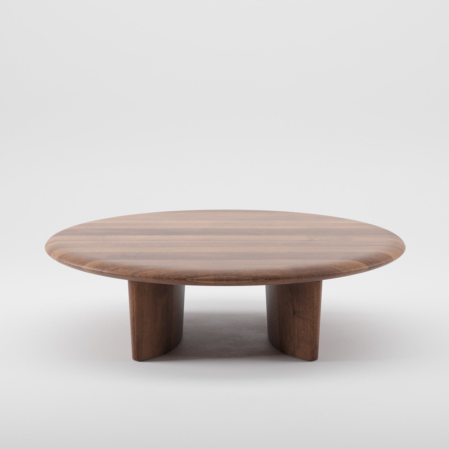 The Artisan MONUMENT Round Coffeetable features a smooth, polished surface and three sturdy legs. Made from solid wood with a rich warm brown finish, it highlights natural grain patterns. Enhanced with natural oils, it is showcased against a plain white background.