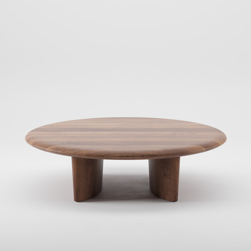 The Artisan MONUMENT Round Coffeetable features a smooth, polished surface and three sturdy legs. Made from solid wood with a rich warm brown finish, it highlights natural grain patterns. Enhanced with natural oils, it is showcased against a plain white background.