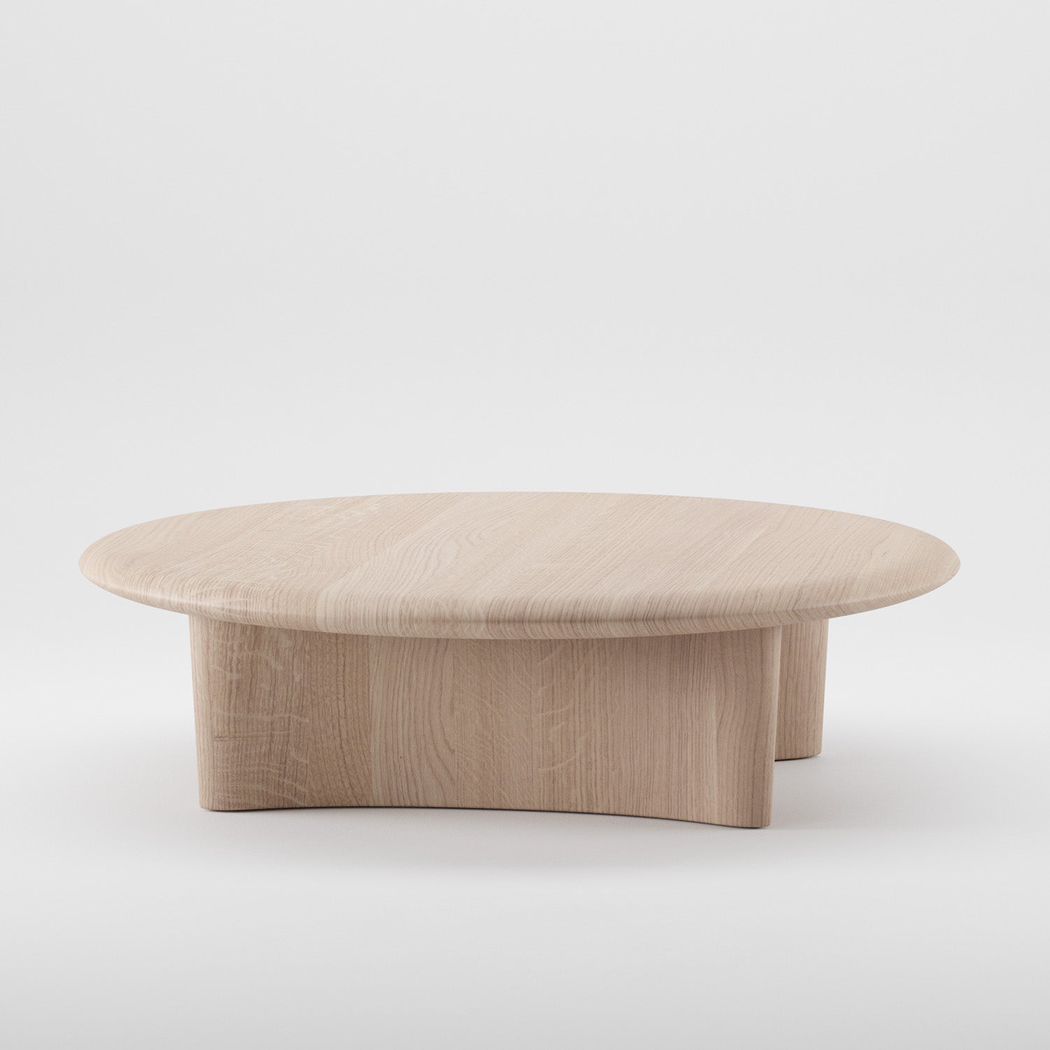 The MONUMENT Round Coffee Table by Artisan features a round, flat top with a curved base made from solid light-colored wood. Its visible grain patterns are enhanced by natural oils and eco-friendly materials, showcased on a plain white background.