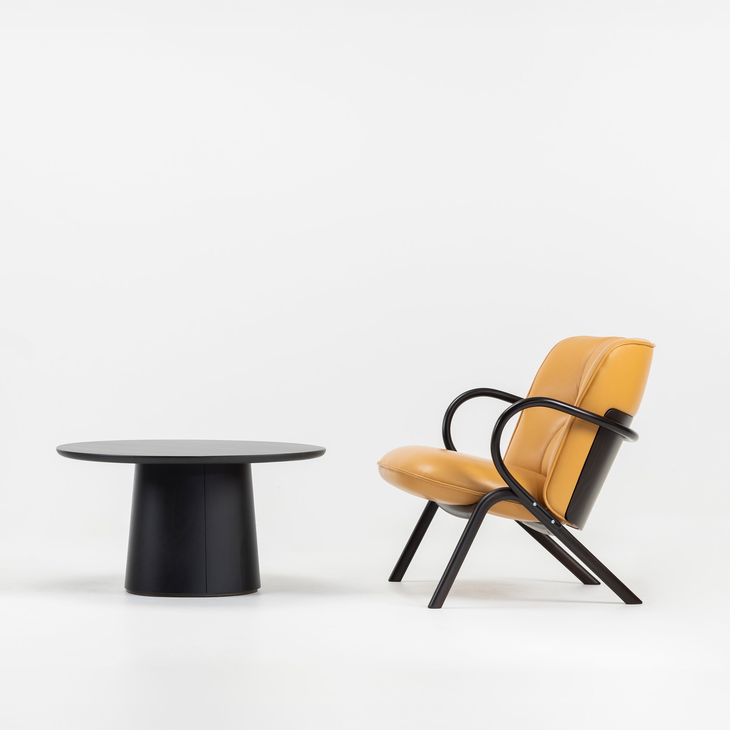 Cissy Lounge Chair Low-Back in mustard upholstery with black bentwood frame beside a black round coffee table.