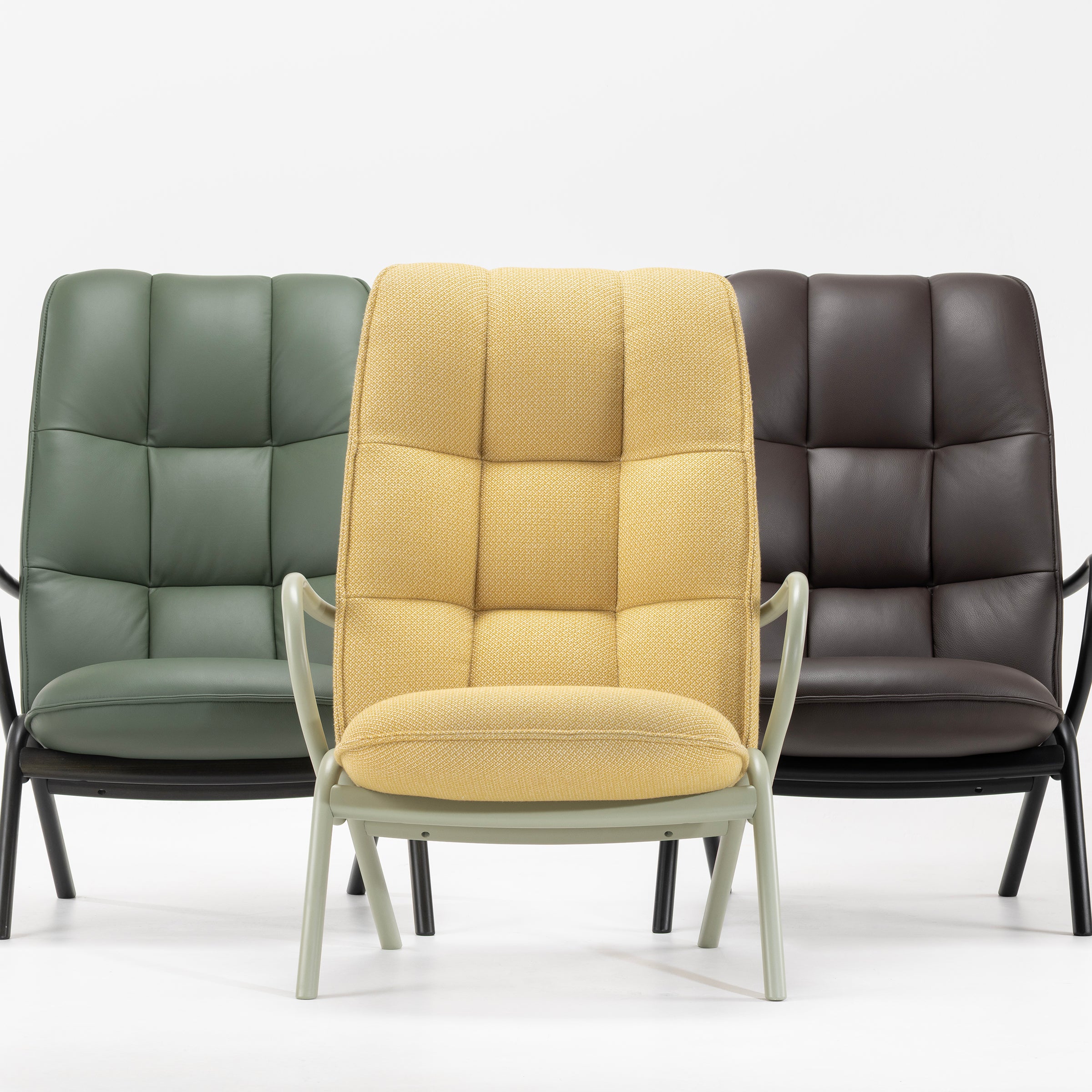 Three Cissy Lounge Chair High-Back models in yellow fabric, green, and dark brown leather upholstery on display.