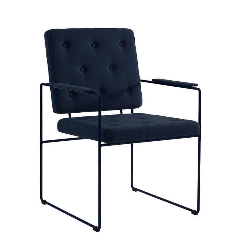 The SWELL TIME Dining Chair by Victor Foxtrot features a dark blue, upholstered seat and backrest with button stitching, complemented by a sleek, minimalist black steel frame with armrests for a contemporary look.