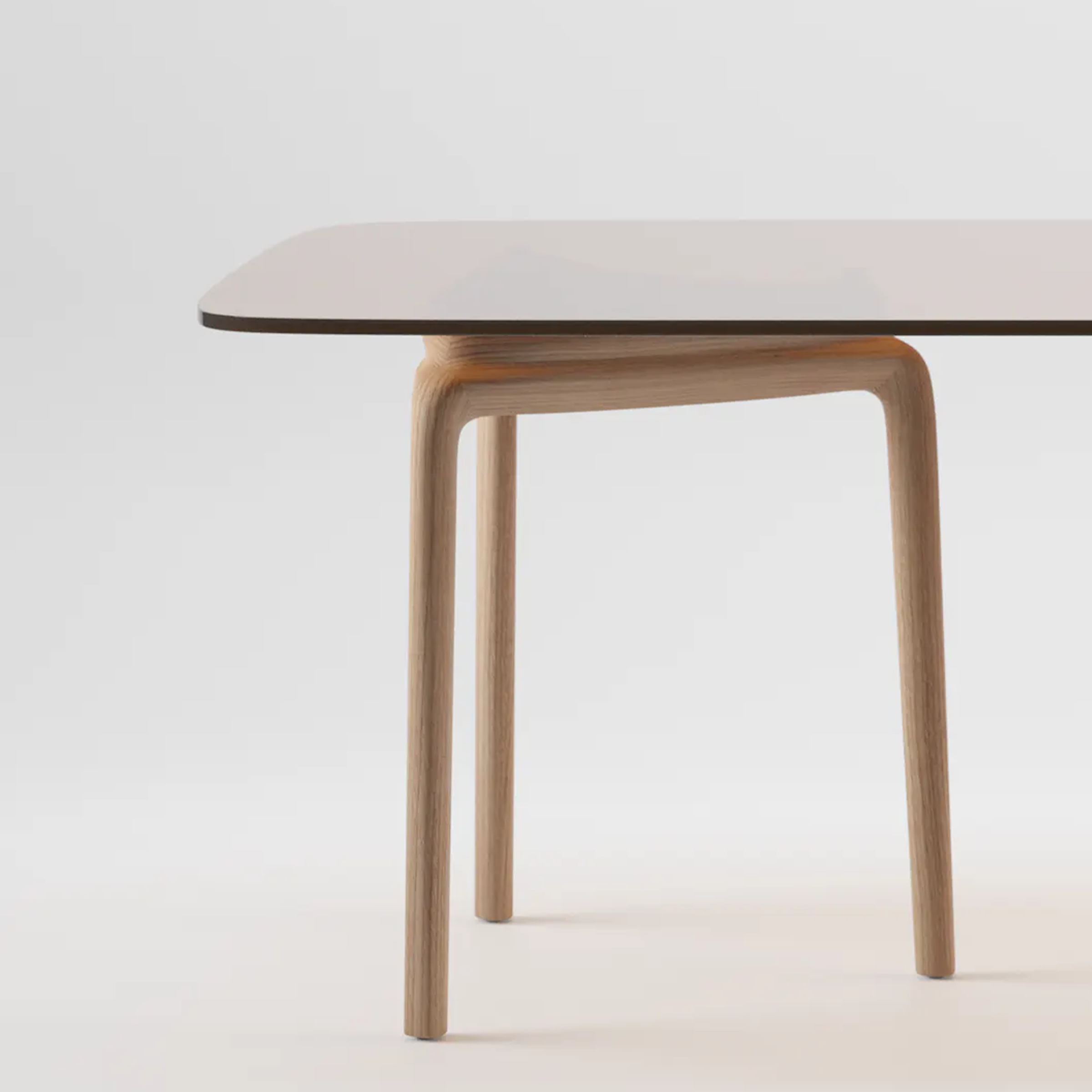 The PASCAL Rectangular Table by Artisan boasts a sleek, dark surface with rounded edges and is supported by a light wood frame made from eco-friendly materials, complete with curved legs. It stands against a plain white background, emphasizing its modern and minimalist design.