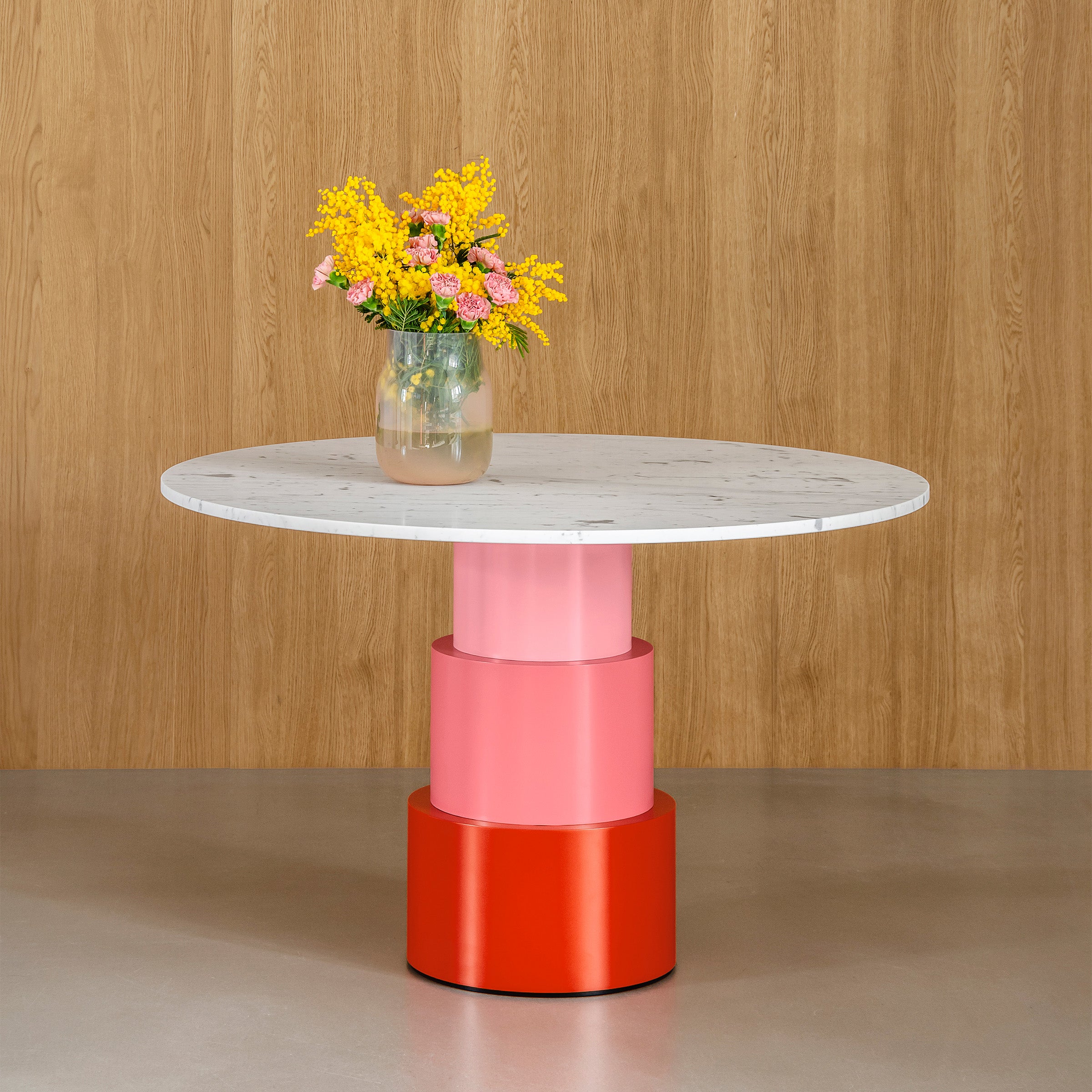 U Turn Table Carrara Marble with tapered tri-cylinder pink and red base and a round marble top with flowers.