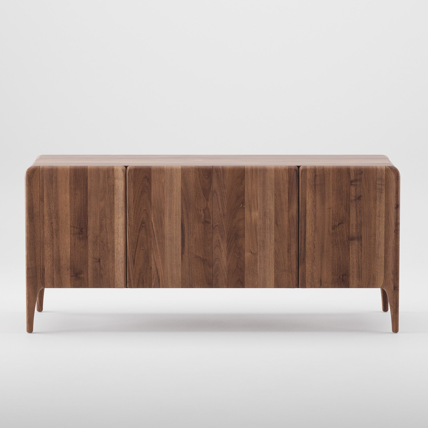 The RIO Sideboard by Artisan is crafted from solid wood with a sleek, minimalist design. It features three doors with subtle grain patterns, four narrow legs, and a smooth finish of natural oils and wax that beautifully complements a plain white background.