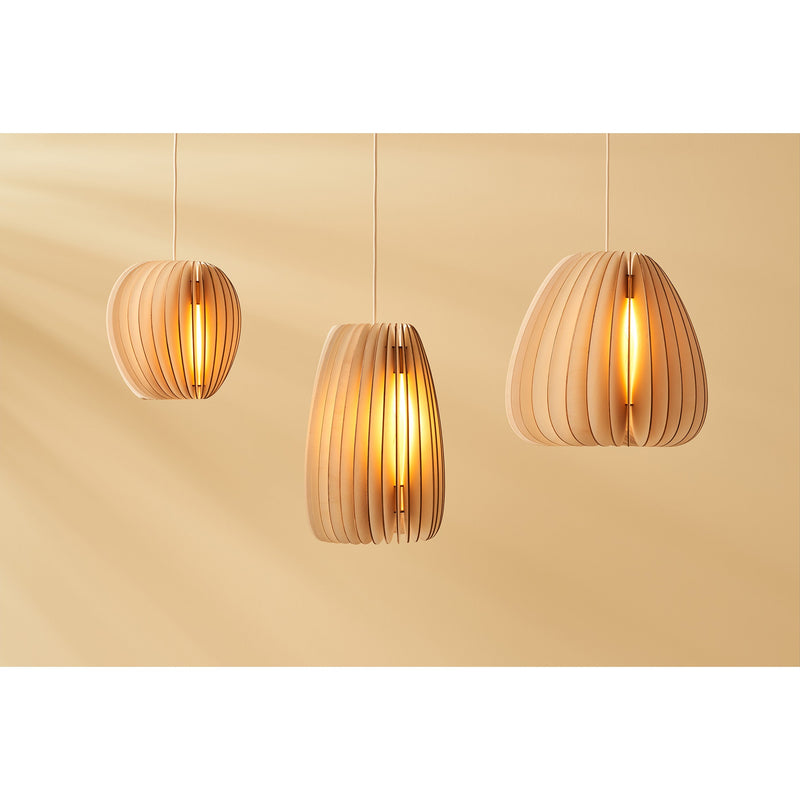 Three Pirum pendant lights by Schneid, featuring a slatted wooden design, hang against a soft beige background. The warm light they emit creates a cozy ambiance, highlighting their organic form and adding an inviting touch to the space.