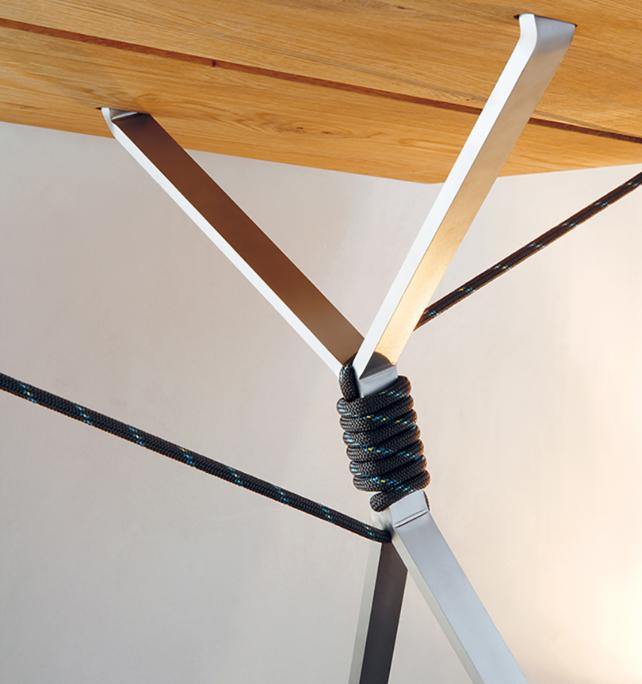 Close-up of the Kampenwand Benchs metal leg design by Moormann. The leg splits into a Y under the wooden seat, secured by black rope coiled around the joint, offering an artistic and modern touch to its structure.