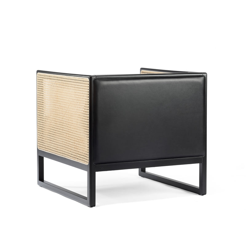 The Armchair Casablanca by TON is a modern black lounge chair with sleek edges, featuring light tan rattan weaving on the back and sides. Its seat and front are upholstered in smooth black leather, while stylish cane weave armrests add an elegant touch to its minimalist design.