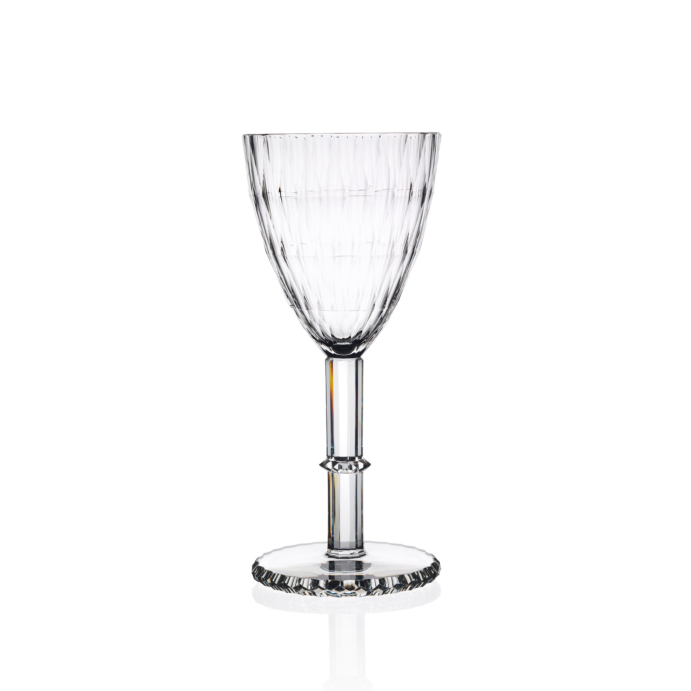 The Lobmeyr Hoffmann Goblet, an intricately cut crystal wine glass with vertical grooves and a decorative stem, crafted from mouth-blown lead-free crystal, stands on a reflective white surface, casting subtle reflections and shadows.