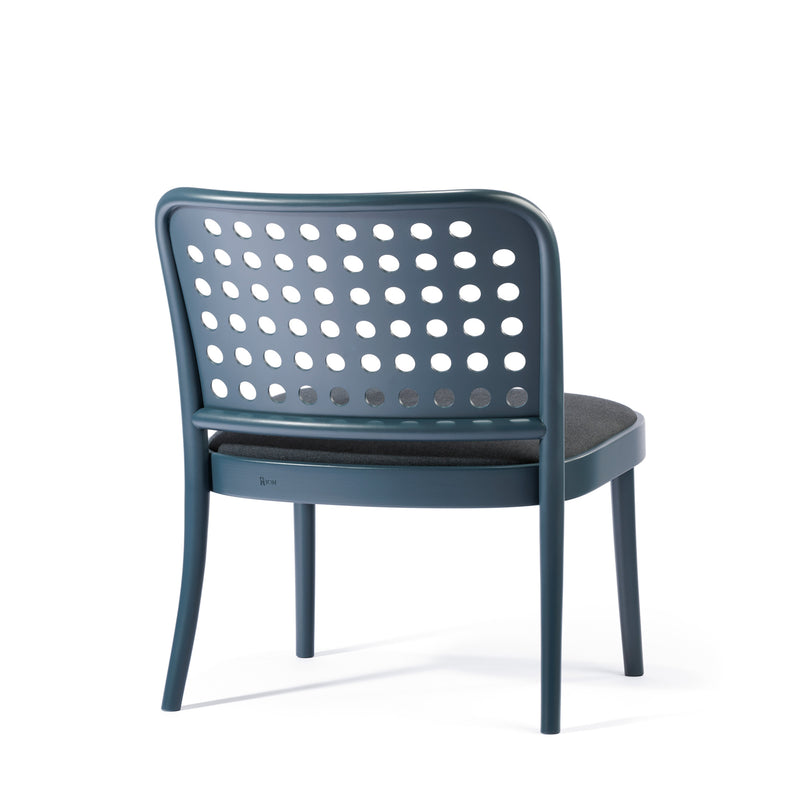The Lounge Chair 822 by TON showcases Scandinavian minimalism with a dark blue frame and perforated backrest featuring circular holes. It has a cushioned seat in dark fabric, all set against a simple white background.