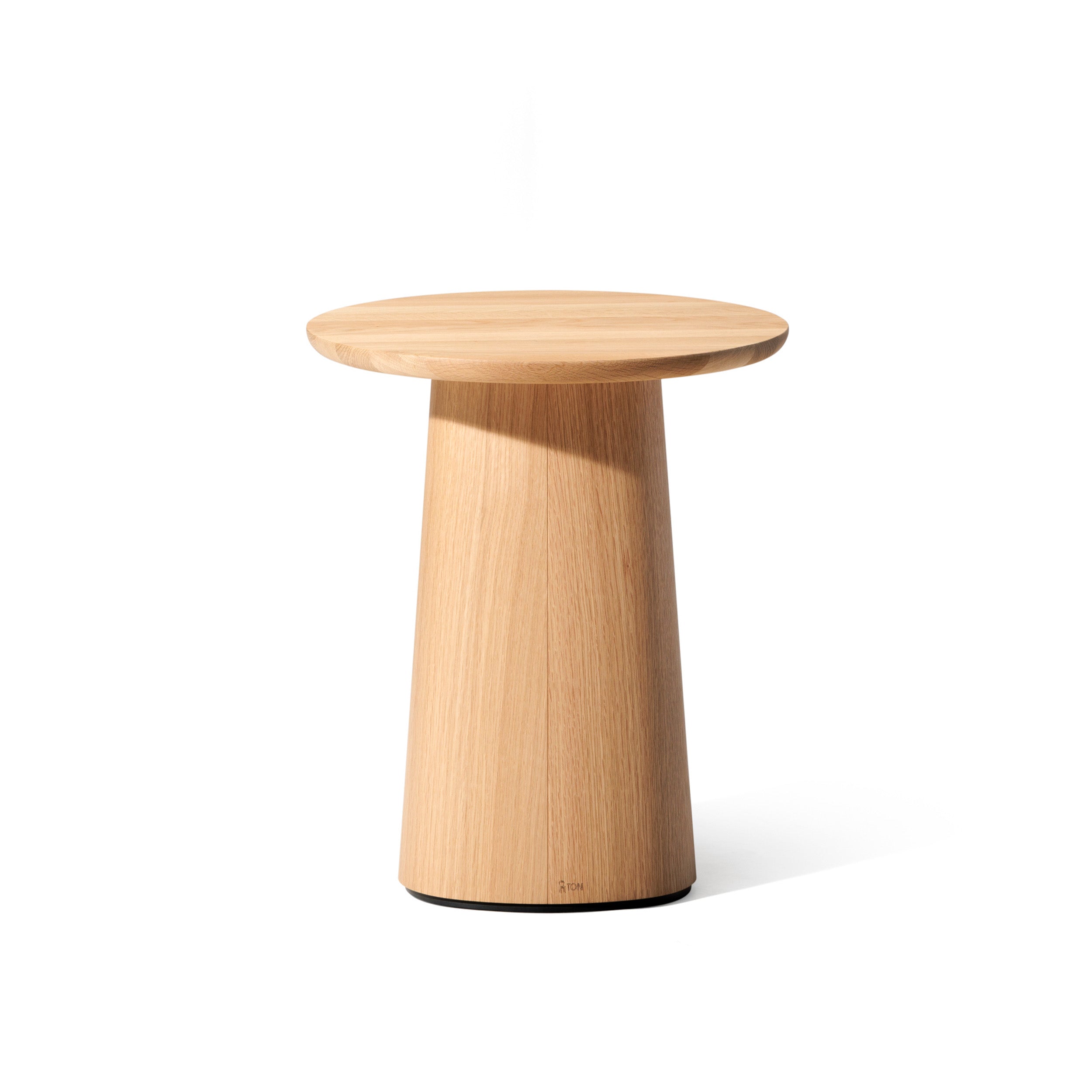 The P.O.V. Coffee Table 473 by TON is a round, light wooden side table with a smooth top and tapered cylindrical base in an organic design against a plain white background. This versatile piece complements various color finishes, ideal as a compact coffee table.