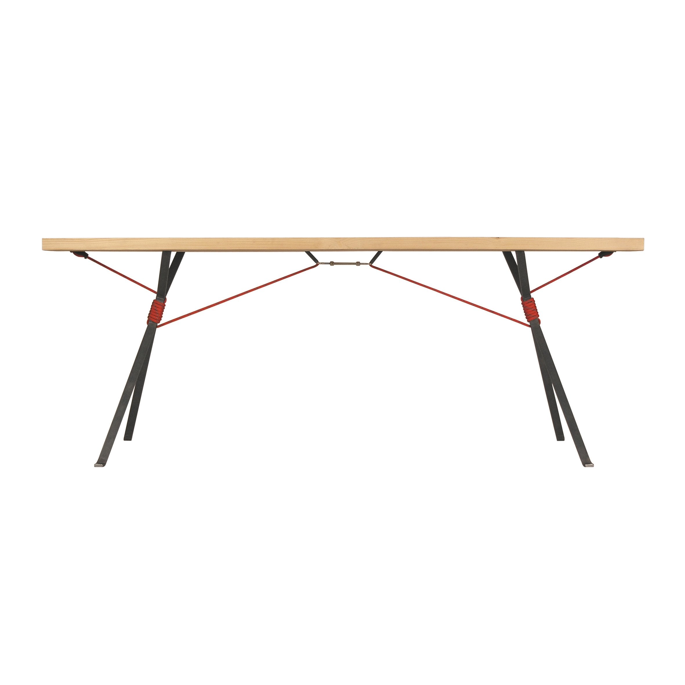 The Moormann Kampenwand Table features a minimalist design with a slim wooden top and angled metal legs, supported by red tension cables. Its modern style highlights the harmonious blend of wood and metal materials.