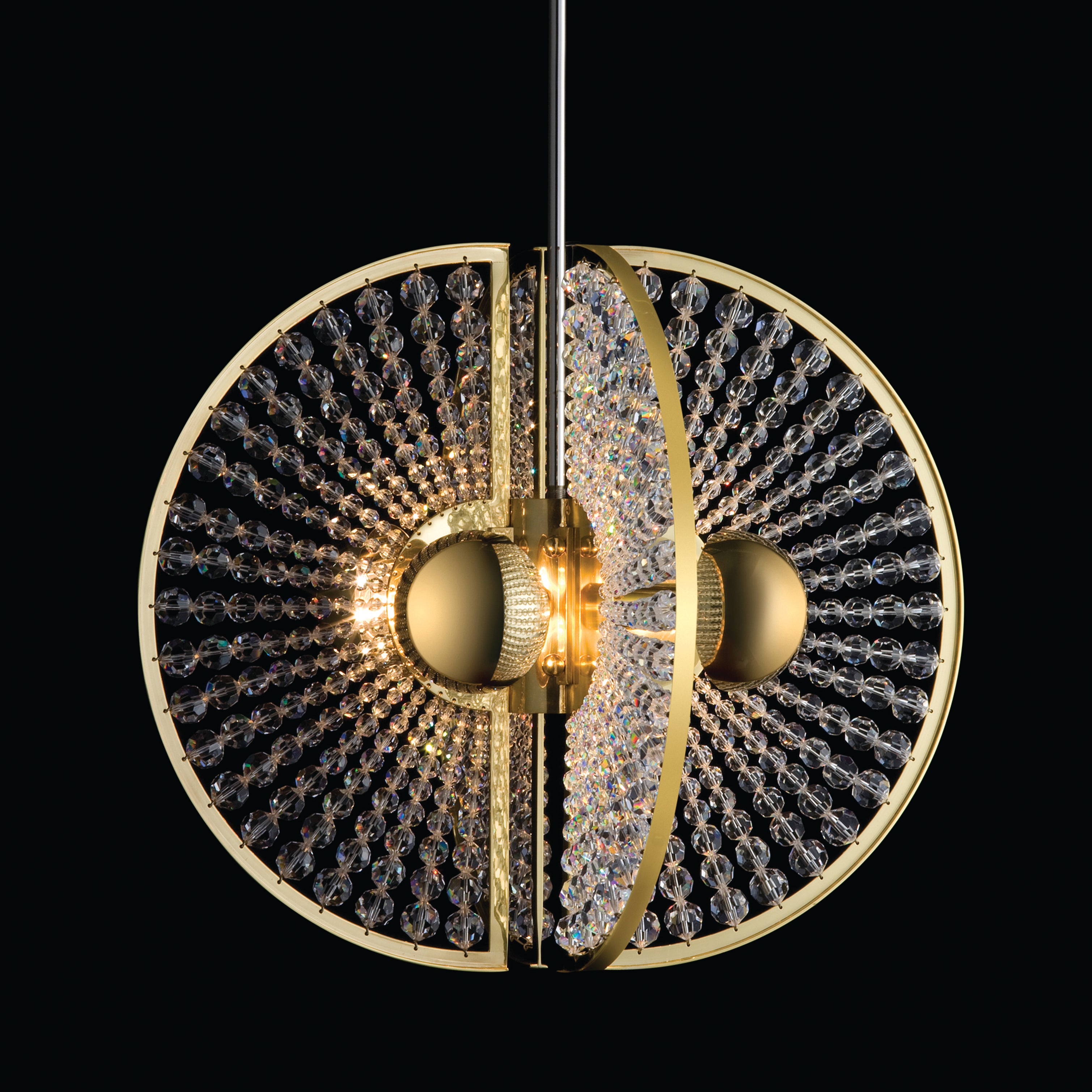 The Lobmeyr Brilliant 6878 by Lobmeyr is a spherical chandelier with a brass frame and Swarovski beads, divided into two halves. Its crystals reflect light from central bulbs, creating a radiant, symmetrical design against a black backdrop.