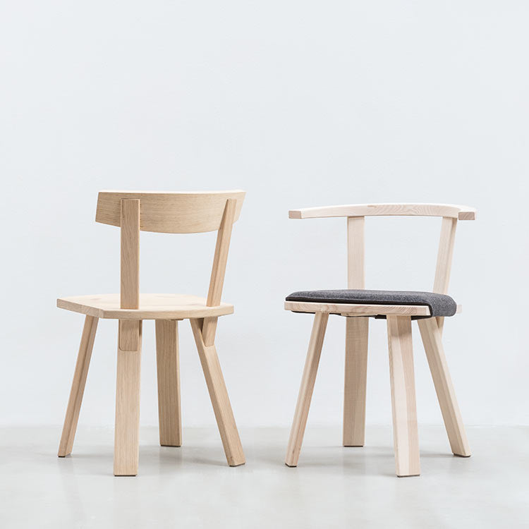 Two modern EOOS-designed wooden Hussl Alpin chairs on a white background: one with a gray fabric cushioned seat, the other fully wood. Both feature minimalist Alpine design and angular legs, showcasing Hussl craftsmanship.