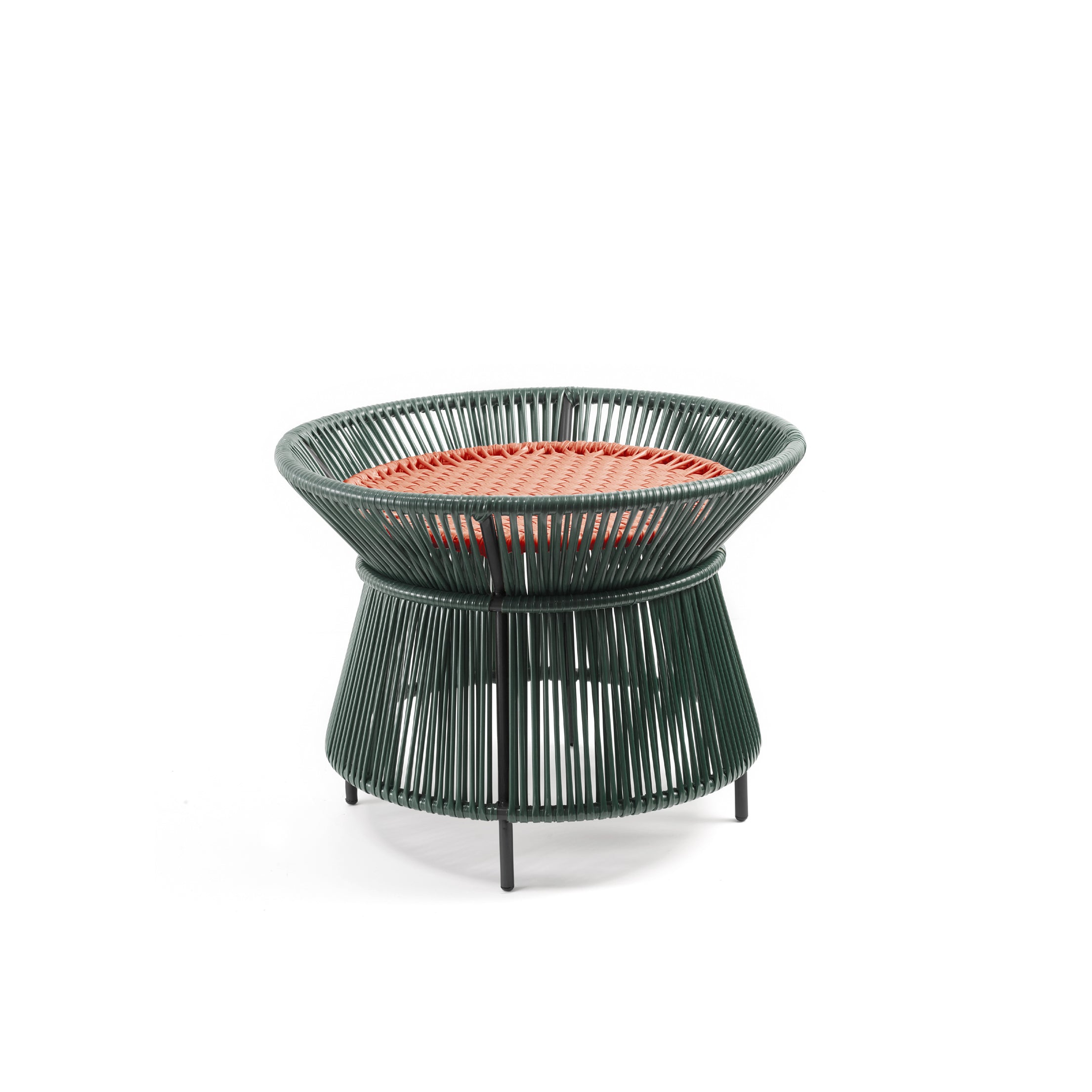 The Caribe Chic Basket Table by Ames is a small, round stool with a green wireframe structure and a red woven top made from recycled plastic cord. Its base slightly flares, standing on short black legs, combining modern minimalism with traditional Momposino weaving.