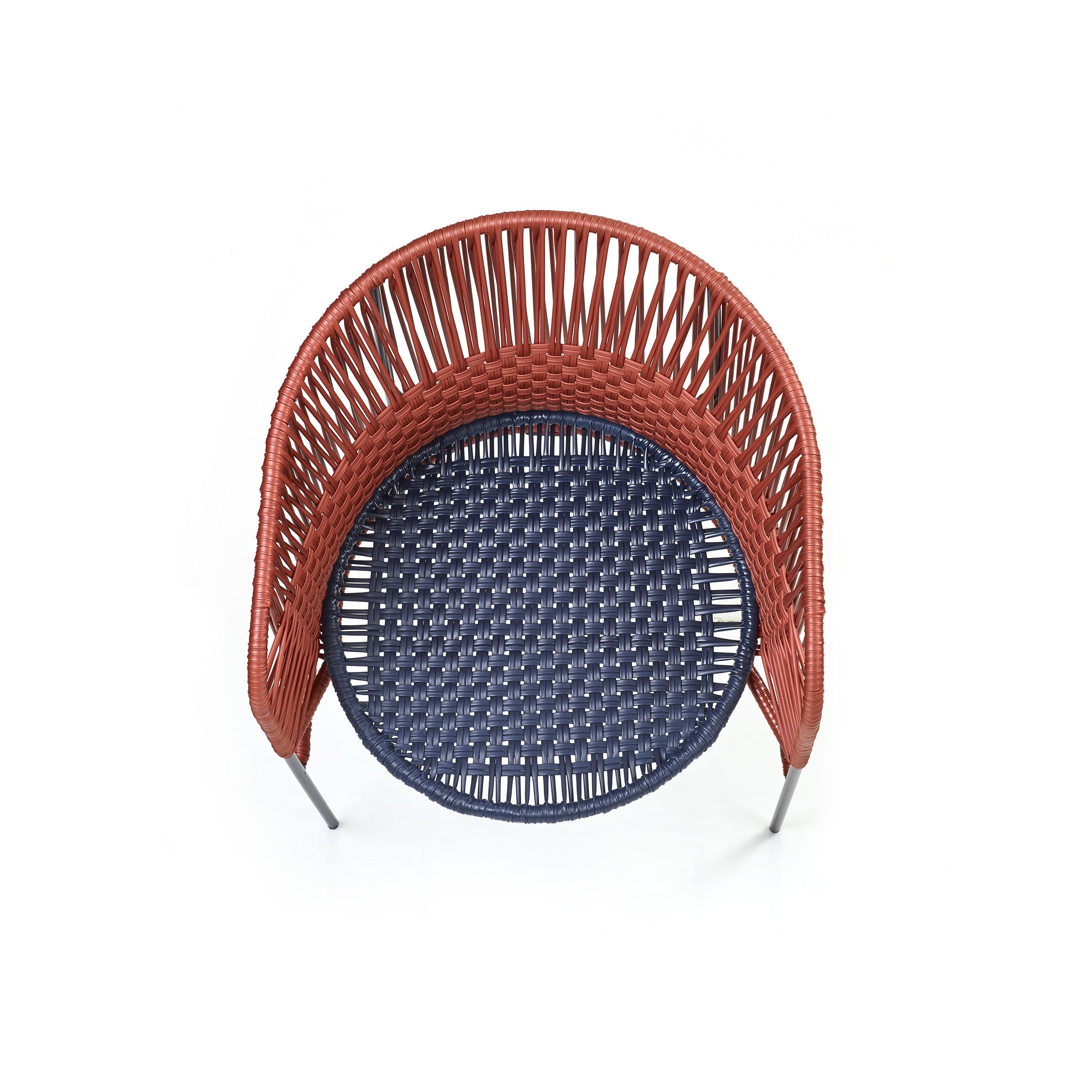 The Caribe Chic Dining Chair by Ames features a top-view wicker design with a round seat. It has reddish-brown woven backrest and sides, a dark blue seat made of recycled plastic cord, and thin metallic legs, all under the artistic direction of Sebastian Herkner.