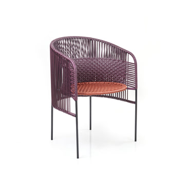 The Caribe Chic Dining Chair by Ames, designed by Sebastian Herkner, features a round, open-back design with a purple woven frame and reddish-brown seat. Standing on four slender black legs, it exudes a contemporary style inspired by the Colombian Caribbean coast.