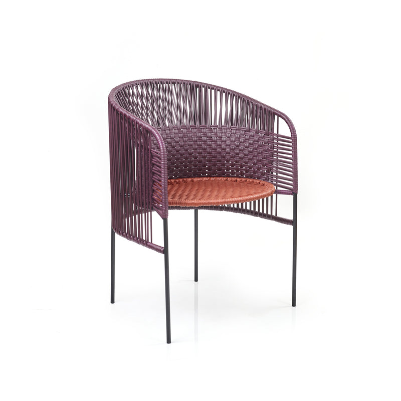 The Caribe Chic Dining Chair by Ames, designed by Sebastian Herkner, features a round, open-back design with a purple woven frame and reddish-brown seat. Standing on four slender black legs, it exudes a contemporary style inspired by the Colombian Caribbean coast.