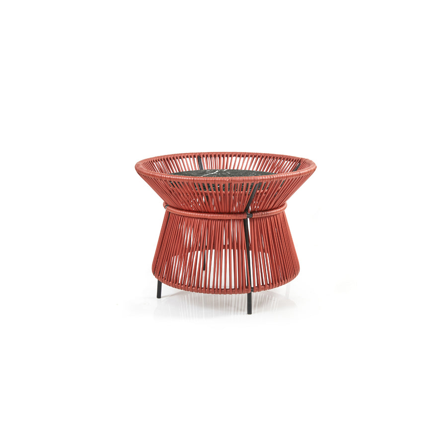 The Caribe Chic Basket Table by Ames showcases a distinctive red design with a flared base and round seat made from recycled plastic cord, supported by sleek black metal legs, all highlighted against a white backdrop.