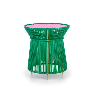 The Ames Caribe High Table by Ames, designed by Sebastian Herkner, features a modern round shape with a green base of vertical rods and a flat pink woven top with yellow details—perfect as colorful, contemporary outdoor furniture.