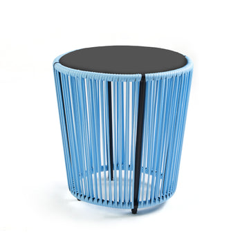 The Cartagenas Sidetable by Ames features a modern design with a black top and blue wire sides, evoking Sebastian Herkners style. Its open, airy look fits beautifully into a coastal metropolis scene, resting gracefully on its flat white surface.