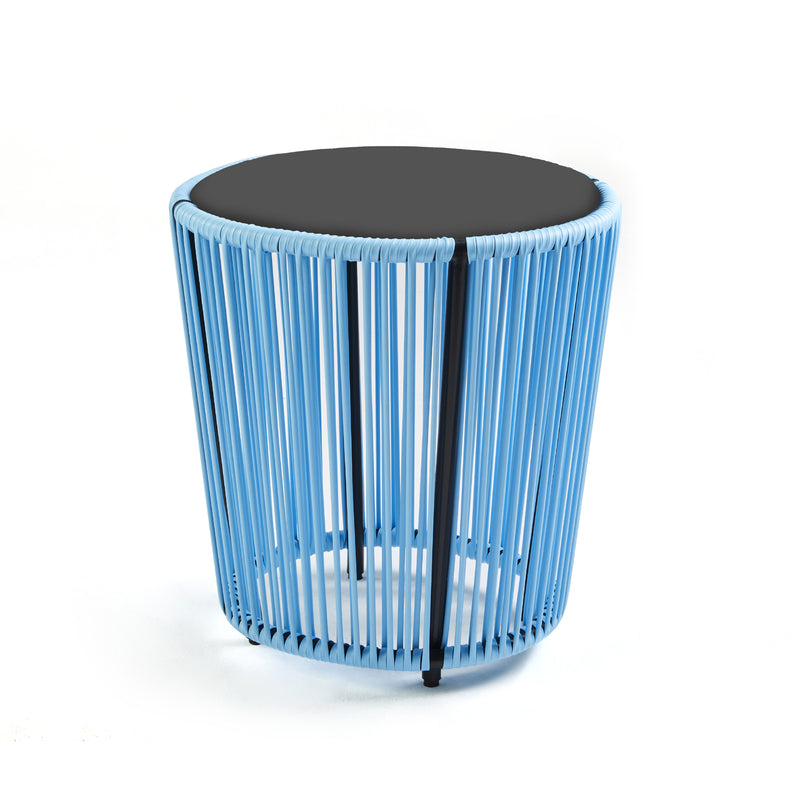 The Cartagenas Sidetable by Ames features a modern design with a black top and blue wire sides, evoking Sebastian Herkners style. Its open, airy look fits beautifully into a coastal metropolis scene, resting gracefully on its flat white surface.