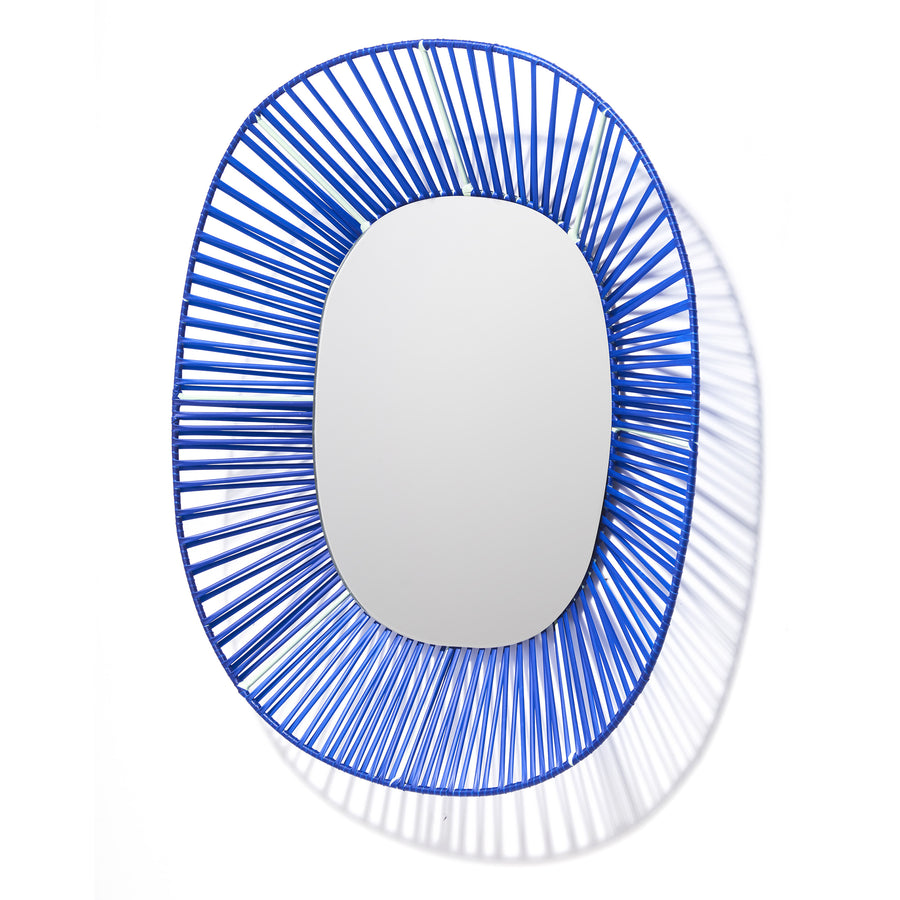 The Cesta Mirror by Ames features an oval design with blue concentric wire framing, forming a sunburst effect. Its vibrant colors cast intricate shadows against white, adding depth and dynamism to any interior.